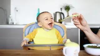 Dziecko siedzi w foteliku i je