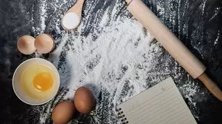 Rozsyupana mąka na blacie kuchennym, jajka, notes