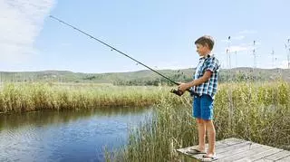 Chłopiec z wędką łowi ryby w stawie