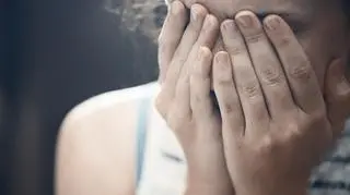 młoda dziewczyna ukrywa twarz w dłoniach