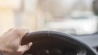 Mężczyzna trzyma kierownicę i patrzy na drogę. 