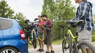 Bagażnik samochodowy na rowery - mężczyźni montują swoje rowery.