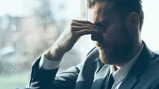 Mężczyzna ma zamknięte oczy i trzyma palcami nasadę nosa