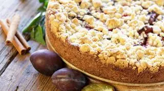 Ciasto drożdżowe ze śliwkami - śliwki leżą obok. Ciasto jest z kruszonką. 