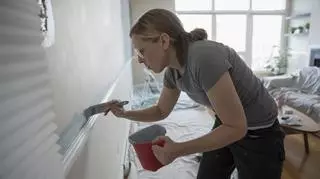 Kobieta maluje pędzlem ścianę 