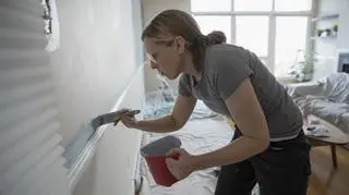 Kobieta maluje pędzlem ścianę 