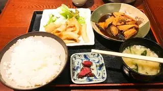 Elementy dania chińskiego na kolorowych talerzach. W tle ryż, sos sojowy 