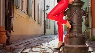 Kobieta w czerwonych spodniach opiera się o kolumnę