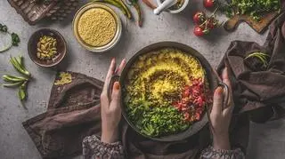 kasza jaglana na śniadanie w misce z warzywami trzymanej w dłoniach