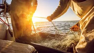 Rybak łowi ryby na łódce siecią