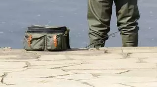 Wędkarz z torbą w woderach na brzegu