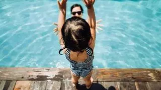 dziecko stojące nad taflą wody basenu