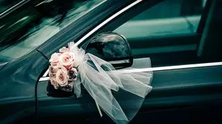 Samochód do ślubu. Czarne auto ozdobione ślubną wiązanką.