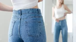 Kobieta w jeansowych spodniach przegląda się w lustrze
