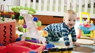 Dziecko raczkuje po dywanie. Obok leżą zabawki interaktywne. 