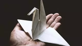 Żuraw origami na męskiej dłoni