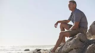 Mężczyzna w szortach siedzi na skale