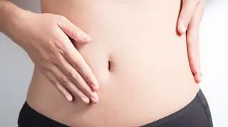Brzuch - kobieta trzyma się za brzuch. Kobiecy brzuch. 