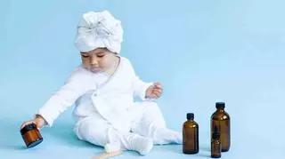 Dziecko bawi się pojemnikami po kosmetykach. 