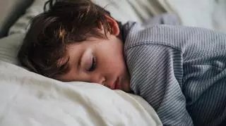 Śpiący chłopiec w pasiastej piżamie.