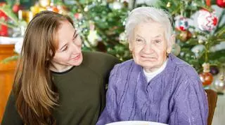 Starsza kobieta i młodsza kobieta siedzą przy stole na tle choinki