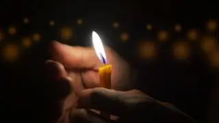 osoba, która trzyma płonącą świeczkę 