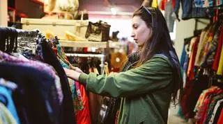 Kobieta przeglądająca ubrania w sklepie z drugiej ręki. 