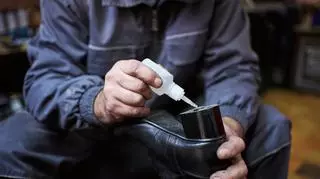 Mężczyzna pokrywający obcas buta klejem. Klej do butów. Naprawa obuwia.