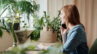 Kobieta przy komputerze rozmawia przez telefon