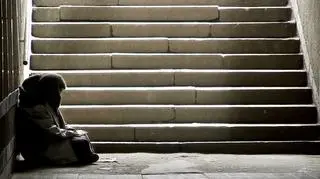 człowiek siedzący przy schodach w podziemiach
