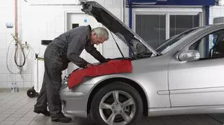 Mechanik pochylający się nad otwartą maską samochodu. 