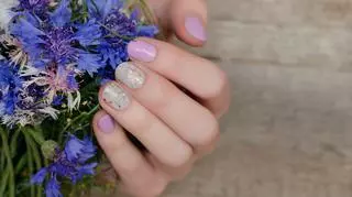 Dłoń kobieca, paznokcie i kwiat