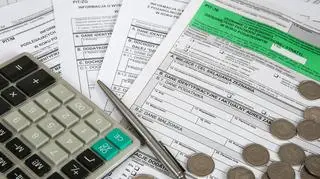 Kalkulator, długopis i pieniądze leżące na formularzach PIT