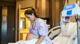 Ciężarna kobieta podczas porodu w szpitalu siedzi na łóżku