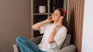 Kobieta słucha muzyki w słuchawkach na fotelu