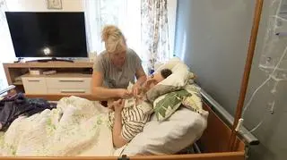 Zajmuje się synem w śpiączce. Stan zajmowanego przez nich mieszkania zagraża jego życiu