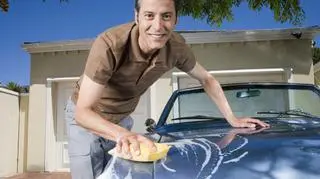 Mężczyzna myjący niebieski samochód.