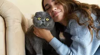 Kobieta przytulająca szarego kota.