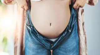 Kobieta w ciąży wkładająca spodnie jeansowe