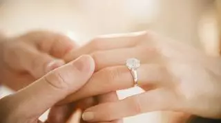 Damska dłoń z pierścionkiem zaręczynowym i męska dłoń