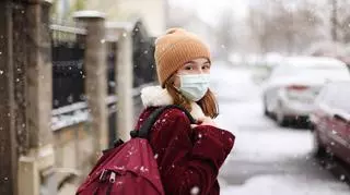 dziecko idące zimą w maseczce do szkoły