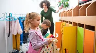 Dziewczynka stojąca przy kolorowych przedszkolnych szafkach. Rekrutacja do przedszkoli.