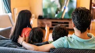 Czteroosobowa rodzina zasiadająca przed ekranem telewizora. 