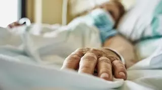 Zbliżenie dłoni pacjenta w szpitalnym łóżku