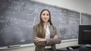 Młoda nauczycielka przed tablicą w sali lekcyjnej