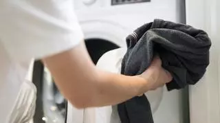 mężczyzna wkłada nowe ubrania do pralki