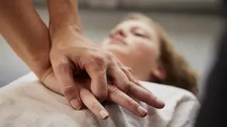 Męskie dłonie uciskające klatkę piersiową kobiety w trakcie czynności resuscytacyjnych 