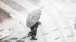 Osoba, która zimowy i śnieżny dzień przechodzi przez ulicę 