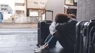 Smutna kobieta siedzi wokół walizek 