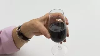 Męska ręka trzymająca kieliszek czerwonego wina